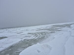 Zamarznięte morze. Śnieg na plaży. Szare, zimowe niebo. Mroźna aura. Zamrznięta woda w Bałtyku.