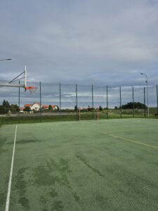 Zielone boisko, linie otaczające boisko do koszykówki. Kosze. Błękitne niebo w ciągu dnia