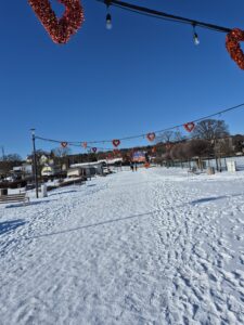 Molo w Krynicy Morskiej zimą. WIszące ozdoby - walentynkowe czerwone serduszka. Biała droga. Błękitne niebo w Krynicy Morskiej nad Zalewem.